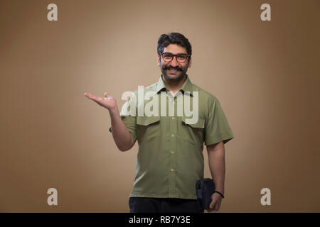 Smiling man wearing eyeglasses tenant un petit sac dans une main et montrant palm. Banque D'Images