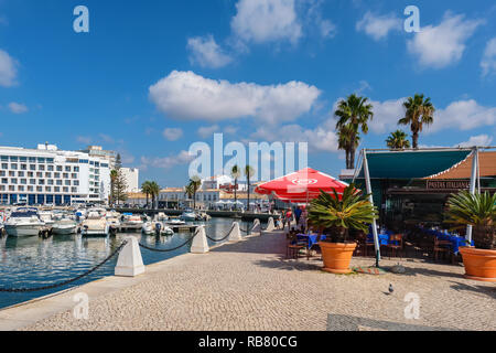 Les touristes à pied le long de la promenade du cours des bateaux à moteur en marina. Faro, Portugal Banque D'Images