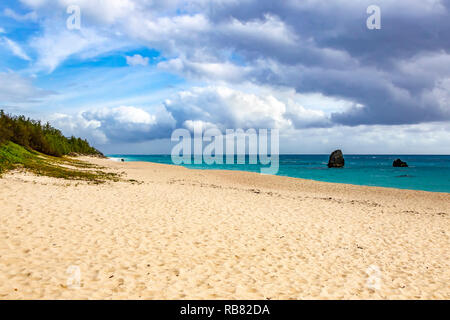 Plage calme avec un couple se promenant dans la distace au bord de l'eau, Hamilton, Burmuda. Banque D'Images