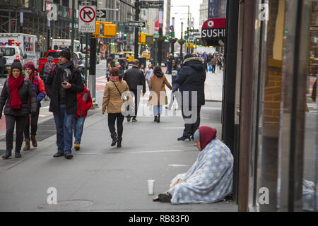 Sans-abri pose assis sur le trottoir en touristes à pied par sur Broadway près du quartier financier de Manhattan. Banque D'Images