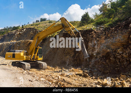 Avec excavatrice marteau hydraulique détruit rock dans la construction routière Banque D'Images
