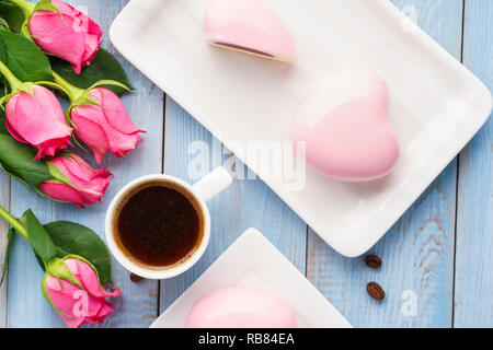 Petit-déjeuner romantique en forme de coeur avec concept gâteaux mousses, de café et de fleurs sur fond bleu pour la Saint-Valentin. Banque D'Images