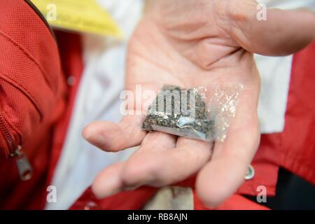 L'ancien Marine Corps PFC. James Krodel, un ancien combattant de la Seconde Guerre mondiale et les autochtones de Quitman, Texas, tient un sac de sable sur les rives d'Iwo Jima qui lui sont données par le maître de 1re classe Josh Lamborn, un yeoman stationnés à la base de la Garde côtière de Honolulu et native de Santa Ana, Californie, avant d'une compagnie américaine honneur vol de retour à Los Angeles à l'Aéroport International d'Honolulu, le 9 décembre 2016. Lamborn servi dans le Marine Corps avant de se joindre à la Garde côtière et avait recueilli un petit peu de sable pendant un déploiement à Iwo Jima. Banque D'Images