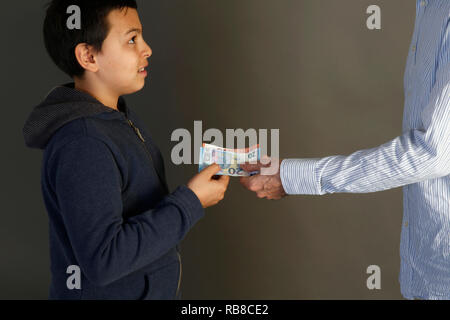Jeune garçon de 12 ans recevant de l'argent d'un adulte. Paris, France. Banque D'Images