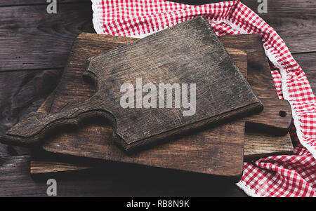 Pile de vieux bois cuisine planches à découper et une serviette rouge sur une table brune, la vue d'en haut Banque D'Images