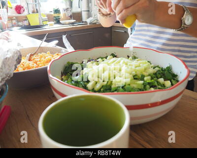 Femme préparant la salade et presser un citron dans la salade. Banque D'Images