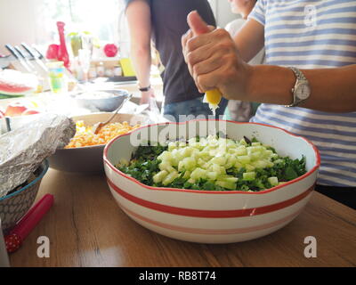 Femme préparant la salade et presser un citron dans la salade. Banque D'Images