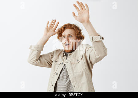 Peur de guy roux timide a été effrayé par l'ami sensibilisation palmiers dans l'abandon de tomber en arrière en terrifyis article expression choquée dans la panique sur fond gris Banque D'Images