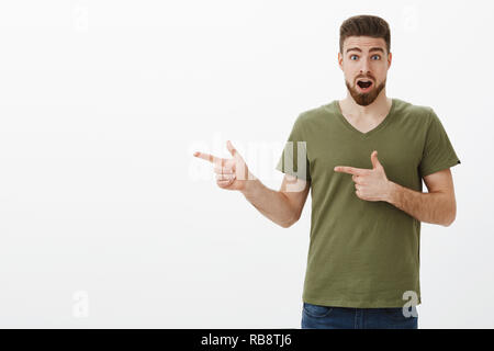 J'adore le vérifier dehors. Portrait de surpris et étonné bon-à guy européenne avec chute de la mâchoire barbe étonnement élever les sourcils et élargir les yeux émerveillés, pointant interrogé sur mur blanc gauche Banque D'Images