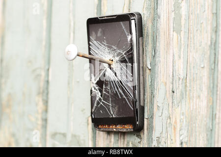 Téléphone mobile obsolète est cloué sur une clôture en bois Banque D'Images