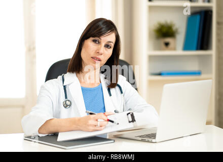 Professionnel sérieux female doctor with clipboard and stethoscope travaillant en hôpital clinique bureau avec naturel dans les soins de professio Banque D'Images