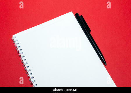 Ordinateur portable Printemps et stylo noir sur des feuilles blanches de papier blanc sur fond rouge. Concept de l'espace libre, copyspace, bloc-notes, livre d'affaires, journal, utiliser pour Banque D'Images