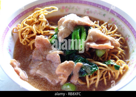 Nouilles frites avec du porc et du brocoli, des aliments traditionnels thaïlandais. Banque D'Images