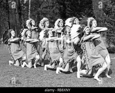 Tous habillés dans les années 1930. Un groupe de jeunes femmes vêtues comme les indiens dans la coiffure de plumes. Banque D'Images