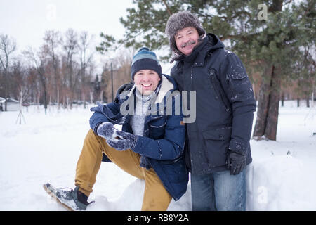 Deux hommes déjà père et fils habillés en vêtements chauds et sniling à la caméra à l'extérieur pendant la randonnée en hiver jour Banque D'Images