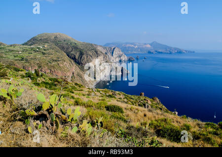 Vue imprenable sur la Valle Muria beach à Lipari et les faraglioni. Dans l'arrière-plan le cratère de l'île de Vulcano. Iles Eoliennes, Sicile Banque D'Images