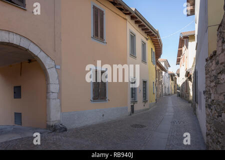 Vue urbaine avec la rue historique de flexion au village historique touristique sur les rives du lac Verbano, tourné en hiver la lumière à Angera, Verbano, Var Banque D'Images