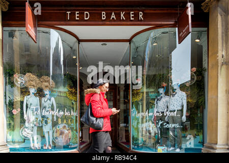 High street Shopping sont illustrés en passant devant un magasin de vêtements de mode Ted Baker vitrine à Bath, Angleterre, Royaume-Uni Banque D'Images