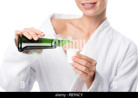 Portrait of smiling woman in bathrobe verser en bouche tasse isolated on white Banque D'Images