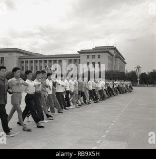 Années 1960, Beijing, Chine, grand groupe de jeunes chinois les hommes en tenue civile faire marhcing clothiing type militaire exerce sur la place Tienanmen l'extérieur de la Grande Salle du Peuple", le Congrès National du Peuple, le Parlement chinois. L'se préparent pour la 'Journée nationale", qui célèbre la fin de la guerre civile chinoise et la création de la République sous le président Mao Zedong. Banque D'Images