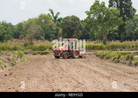 Les agriculteurs thaïlandais sont à l'aide d'un tracteur pour préparer le sol pour cultiver le riz. Banque D'Images