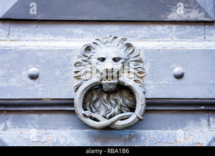 Heurtoir vintage extérieur sous forme de cercle de métal avec lion serpent sur une porte en bois bleu d'un bâtiment ancien, à Catane, Sicile, Italie. Banque D'Images