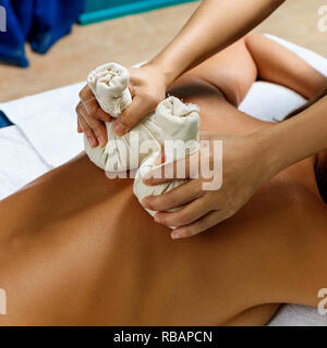 Young woman getting massage aux herbes chaudes sacs. Banque D'Images