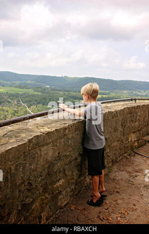 Un jeune garçon est debout sur ses pieds, tenant sur une balustrade et à au-dessus d'une falaise sur un Scenic oublier dans la petite ville américaine du midwest s sur un Banque D'Images