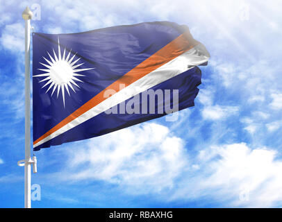 Drapeau national des Îles Marshall sur un poteau en face de ciel bleu. Banque D'Images