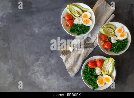 Le quinoa cuit avec des bols de bouddha les tomates, l'avocat, le chou vert, œufs durs et du yaourt grec sur fond de béton gris. Petit déjeuner sain. Vue d'en haut. Copier sp Banque D'Images