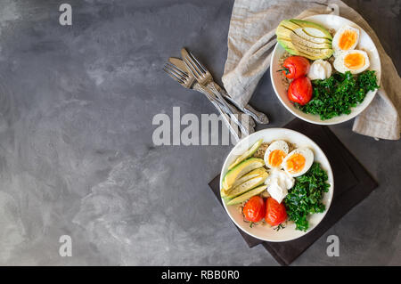 Le quinoa cuit avec des bols de bouddha les tomates, l'avocat, le chou vert, œufs durs et du yaourt grec sur fond de béton gris. Petit déjeuner sain. Vue d'en haut. Copier sp Banque D'Images