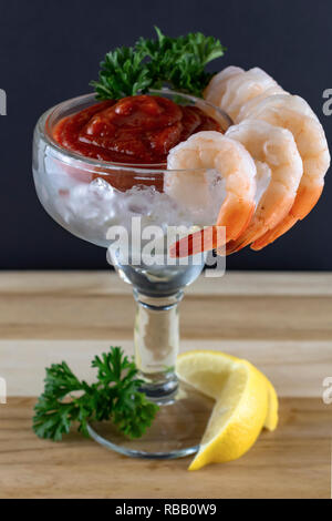 Un cocktail de crevettes en verre de margarita. Hung de la crevette sur la jante avec sauce cocktail à l'intérieur avec du persil et de la glace. Fond noir Banque D'Images