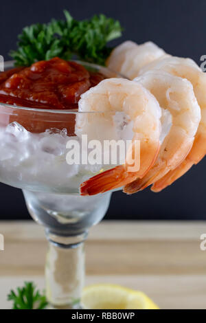 Un cocktail de crevettes en verre de margarita. Selective focus sur les crevettes suspendues à côté. Le persil et la sauce cocktail en tasse avec de la glace. Le citron et le persil à la base o Banque D'Images