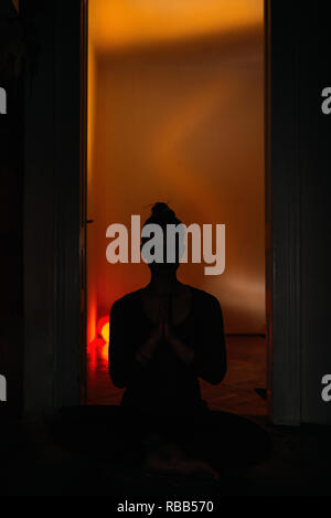 Silhouette de jeune femme professeur de yoga méditation assis sur un tapis sur le plancher dans un costume uni noir étant prêt pour un excellent entraînement. Tonique imag Banque D'Images