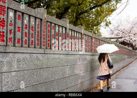 Femme avec parapluie marche sur la rue japonaise à Tokyo Banque D'Images