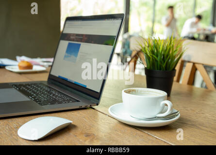 Ordinateur portable avec la souris et tasse de café sur la table à café. Banque D'Images