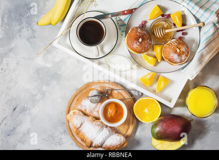 Petit-déjeuner servi avec café, jus d'orange, croissants, beignes et les fruits sur bac blanc Vue de dessus Banque D'Images