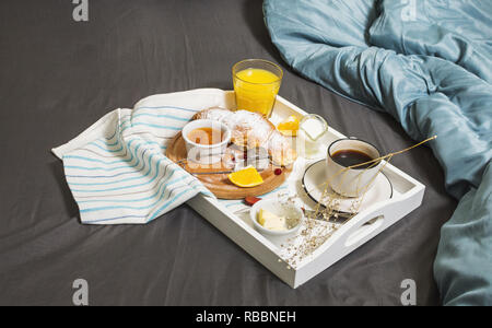 Petit-déjeuner au lit avec café, croissants et jus d'orange sur fond blanc. Banque D'Images