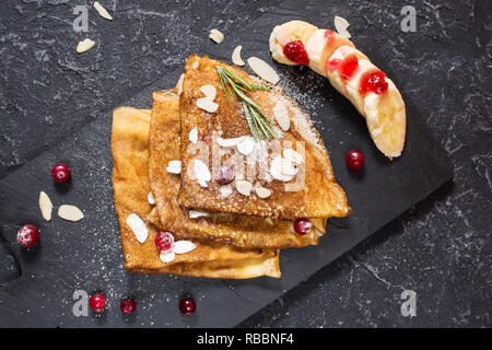 Crêpes traditionnelles de banane et fruits rouges sur fond noir en noir Banque D'Images