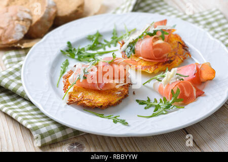 Rosti de pommes de terre du sud du Tyrol avec bacon, fromage parmesan et roquette servi sur une plaque blanche Banque D'Images