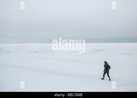 Seul l'homme hiker with backpack aller sur la côte de la mer d'hiver. La composition minimaliste. Banque D'Images