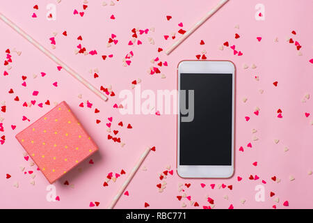 Saint-valentin, téléphone sur fond rose avec des coeurs rouges et des boîtes de cadeaux, d'amour et de connexion entre eux, photo romantique, convient pour adver Banque D'Images