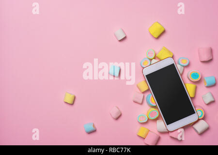 Les guimauves avec smartphone, sur fond pastel, la décoration de l'amour et la Saint-Valentin concept. Banque D'Images