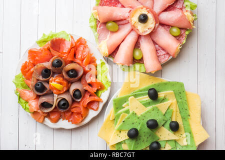 Trois assiettes d'entrées. Rouleau de jambon avec le fromage et le poisson rouge, différents types de fromages en tranches Banque D'Images