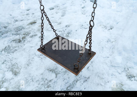 Swing vide en hiver avec la neige couvrant une aire de jeux pour enfants Banque D'Images