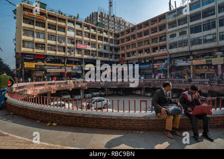 Vue sur une cour à Nehru Place, New Delhi, Inde, qui est la plaque tournante de la technologie numérique : scène montre deux personnes en premier plan assis au soleil. Banque D'Images
