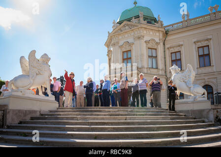 Groupe d''été, les visiteurs de la Schloss Belvedere à Vienne l'écoute de leur guide lors d'une visite de ses célèbres jardins paysagers, Wien, Autriche. Banque D'Images