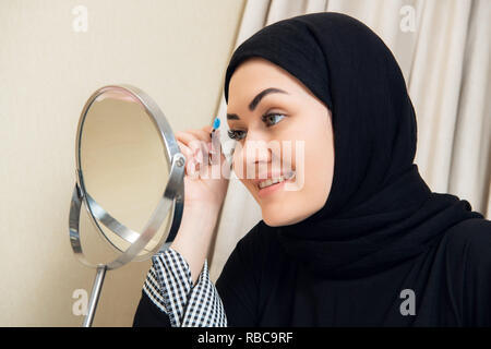 Belle femme musulmane le mascara. Jeune femme arabe à l'aide de brosse lash Banque D'Images