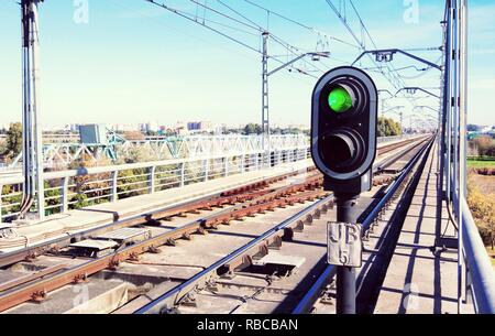 Feu de circulation en vert sur les rails du métro avec des caténaires sur les voies et ciel bleu en arrière-plan Banque D'Images