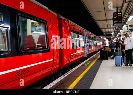 Londres, Royaume-Uni - Juin 28, 2018 : Gatwick Express avec métro métro rouge à la gare Victoria de Londres, les gens qui attendent sur la station de plate-forme Banque D'Images